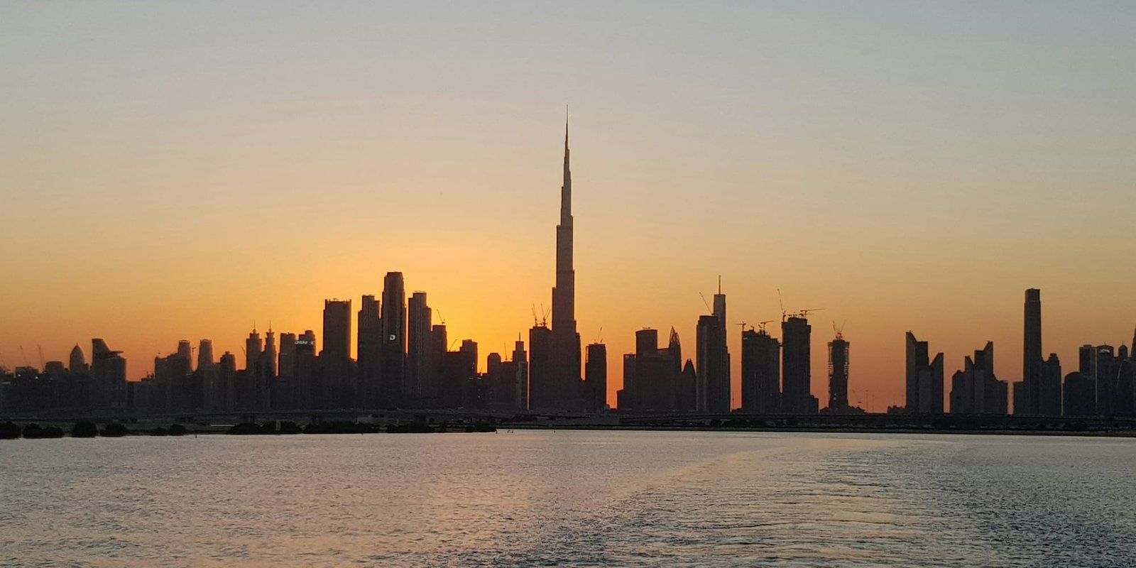 High-rise towers on the Dubai skyline at sunset, seen across the water